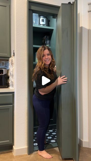 a woman is standing in front of an open cabinet with her hand on the door