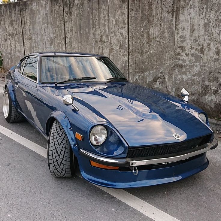 a blue sports car parked next to a concrete wall