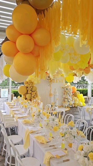 tables with white chairs and yellow balloons hanging from the ceiling