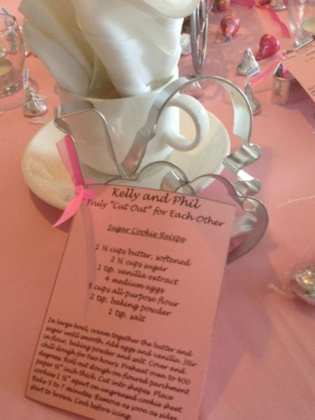 a pink table cloth with some white napkins and silverware on top of it