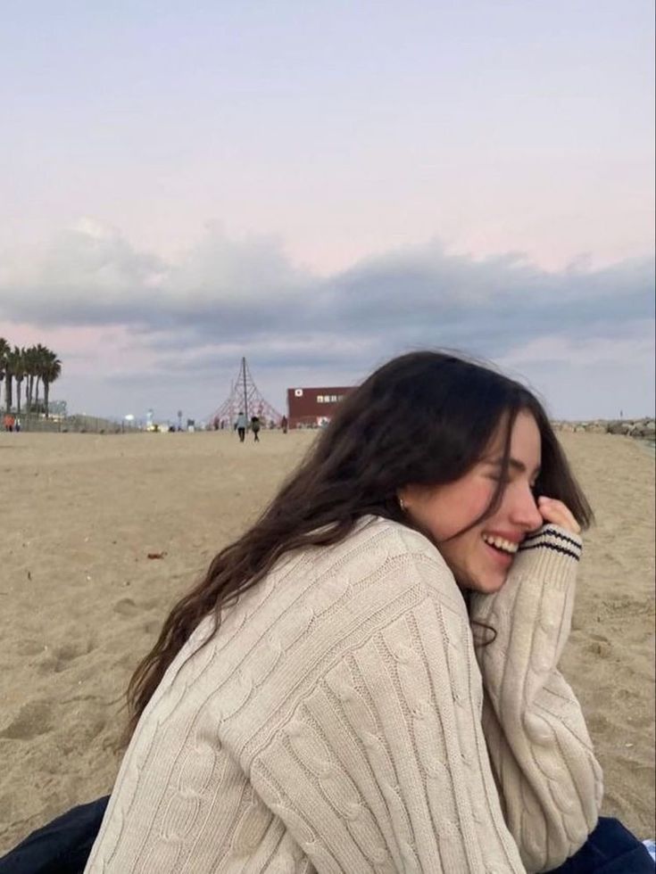 a woman sitting on top of a sandy beach