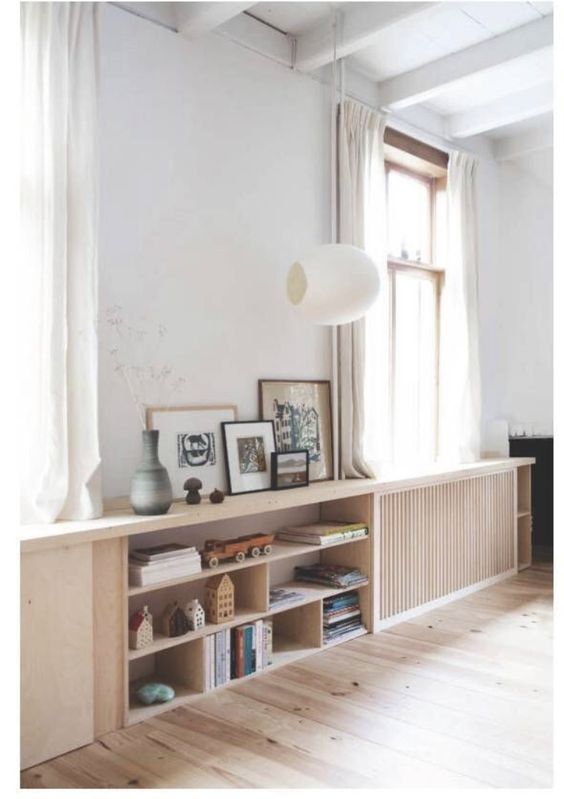 a living room with some bookshelves and pictures on the wall next to a window