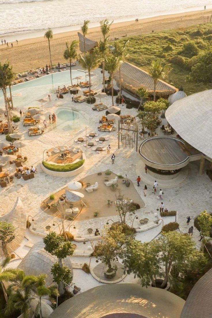 an aerial view of a beach resort next to the ocean with people walking around it