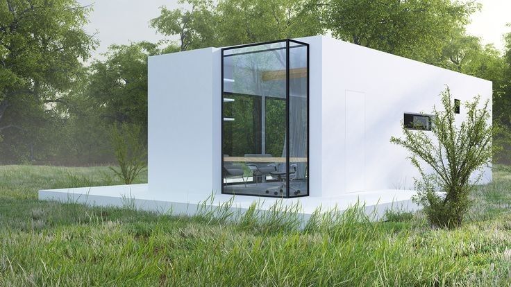 a small white building sitting on top of a lush green field next to a forest