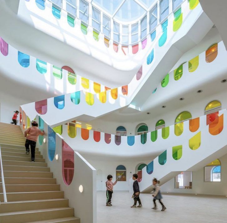 children are walking up and down the stairs in a large building with multicolored glass windows