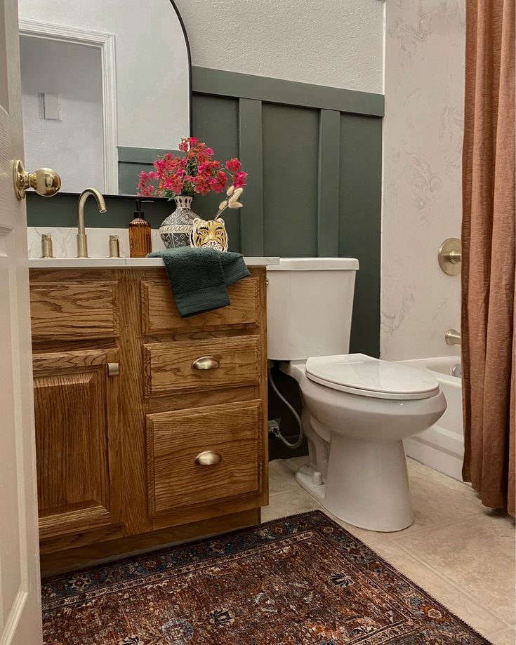 a white toilet sitting next to a wooden sink vanity in a bathroom under a mirror