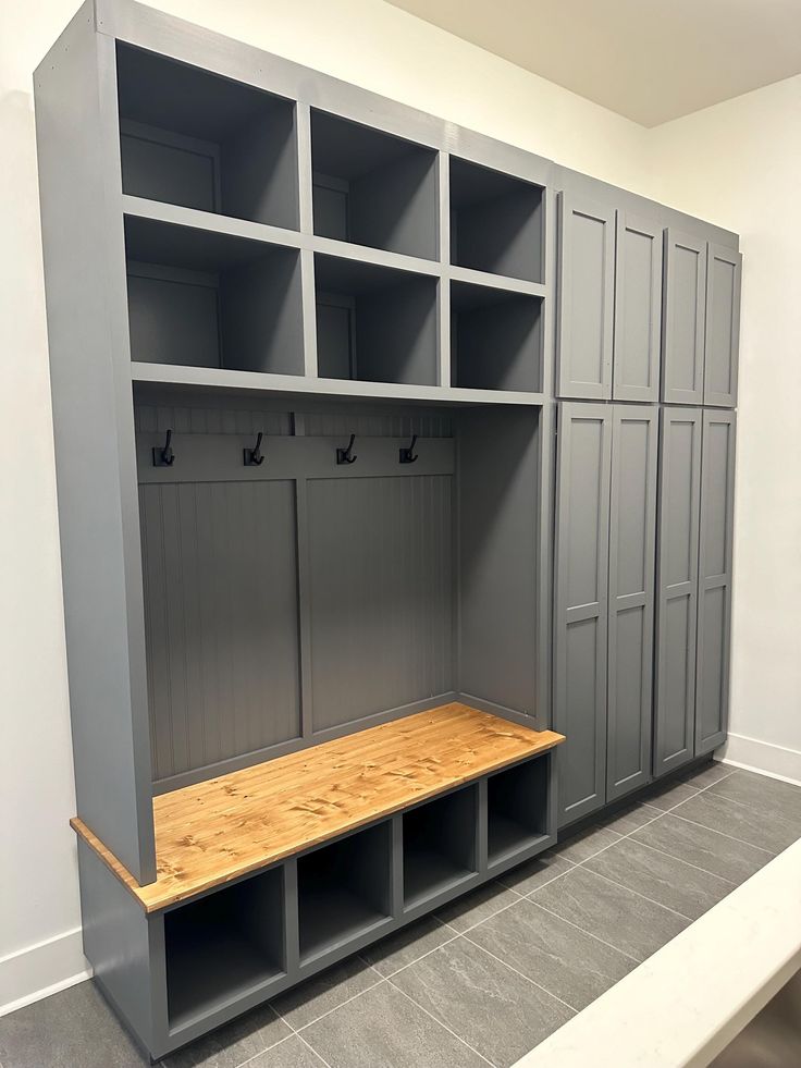 a room with several gray lockers and wooden bench