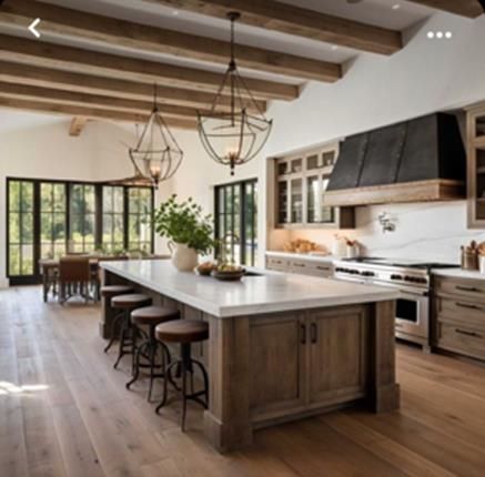 a large kitchen with wooden floors and white walls, has an island in the middle