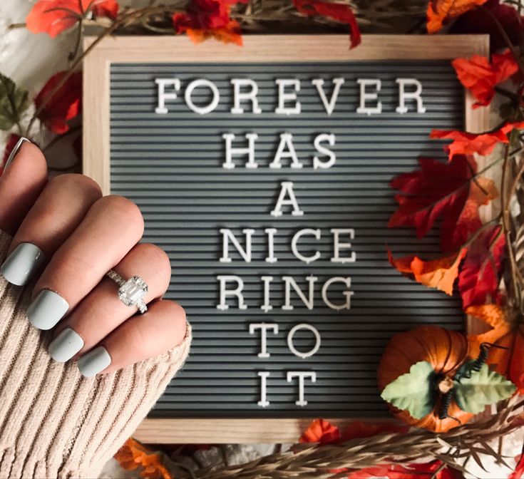 a woman's hand holding a ring in front of a sign that says forever has a nice ring to it