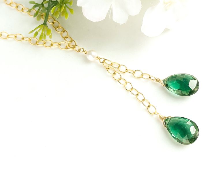 This lariat necklace features two lovely green quartz briolette gemstones. The color of the quartz is a deep green - very rich and vivid! The green contrasts nicely with the bright gold of the chain. In the center of the necklace is a white Swarovski pearl. MATERIALGold filled chainSwarovski crystal pearlGenuine green quartz briolette stonesSIZE15x10mm green quartz stones16-inch chain (excluding lengths of drops)5mm Swarovski pearlCLOSURELobster claspWHAT IS GOLD FILLED?We used to have just 2 ch Elegant Green Lariat Necklace As Gift, Green Dangle Lariat Necklace As Gift, Green Lariat Necklace For Gifting, Green Lariat Necklace For Gift, Green Dangle Lariat Necklace For Gift, Elegant Green Lariat Necklace, Elegant Gold Briolette Emerald Necklace, Luxury Briolette Drop Necklace, Luxury Gold Briolette Drop Necklace