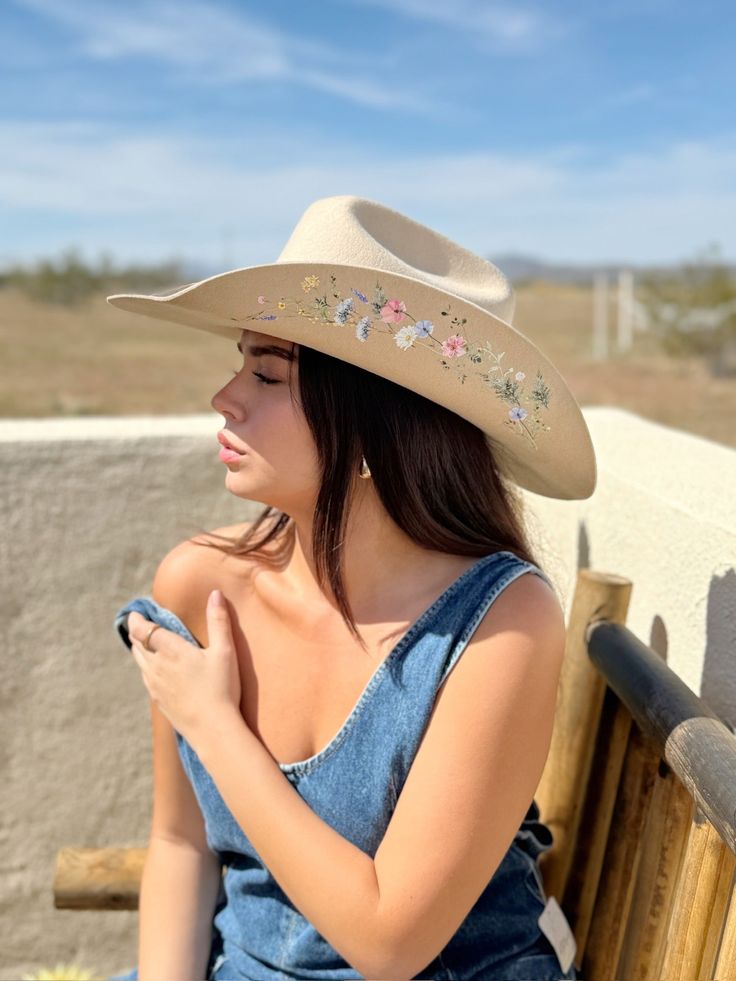 Introducing The Katie Lou—a tribute to delicate beauty and untamed spirit. Handcrafted from luxurious, sustainable Australian wool, The Katie Lou showcases an intricate array of delicate wildflowers, adding a touch of nature’s splendor to its classic cowboy shape. The artistic detailing creates a romantic, ethereal aesthetic perfect for those who live unapologetically free. With every stitch and brushstroke, this hat captures the essence of "spirits by the fire"—perfect for bonfire nights, count Adjustable Felt Hat For Summer Country Events, Adjustable Felt Hat For Country Summer Events, Adjustable Summer Felt Hat For Country Events, Western Cream Straw Hat For Country Events, Adjustable Country Style Felt Hat For Summer, Beige Fitted Felt Hat For Summer, Fitted Beige Felt Hat For Summer, Cream Country Style Straw Hat For Ranch, Country Style Cream Straw Hat For Ranch