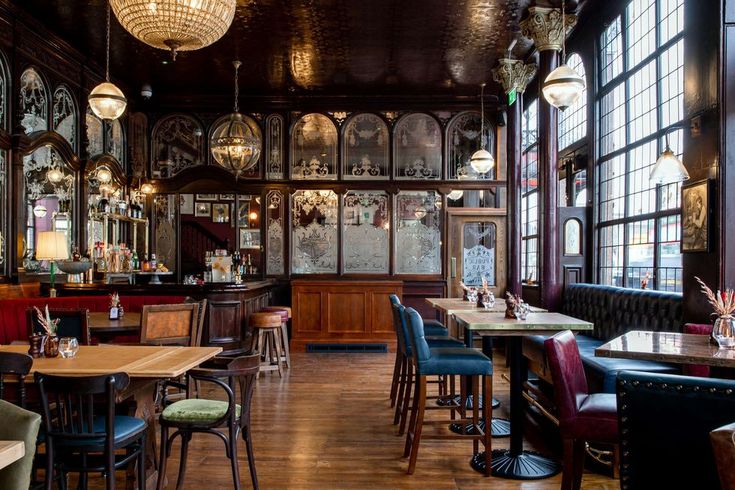 the interior of a restaurant with wooden tables and chairs, chandeliers hanging from the ceiling