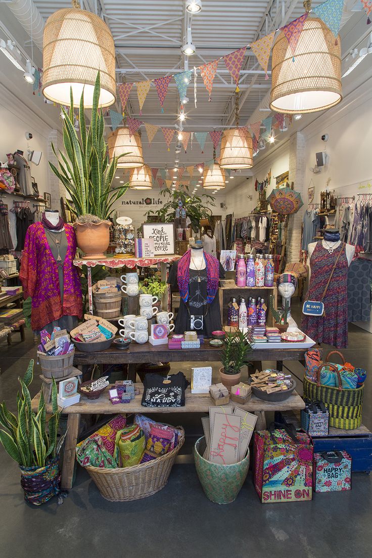 the inside of a store filled with lots of items and plants in baskets on tables