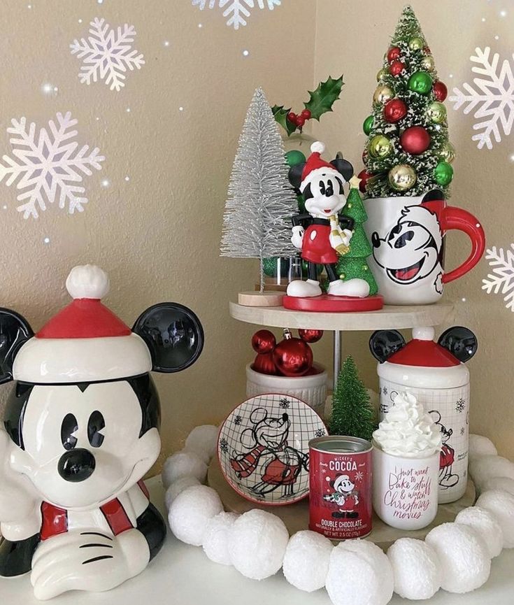 mickey and minnie mouse figurines are sitting on a shelf in front of a christmas tree