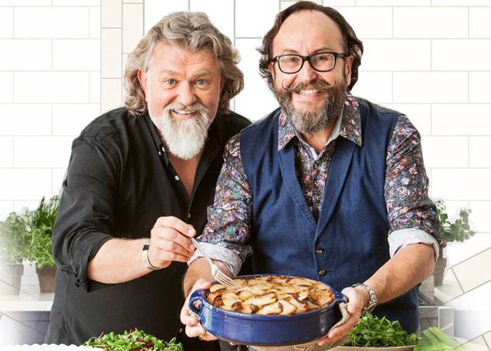 two men standing next to each other holding a bowl of food