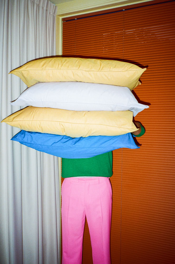 three pillows are stacked on top of each other in front of a curtained window