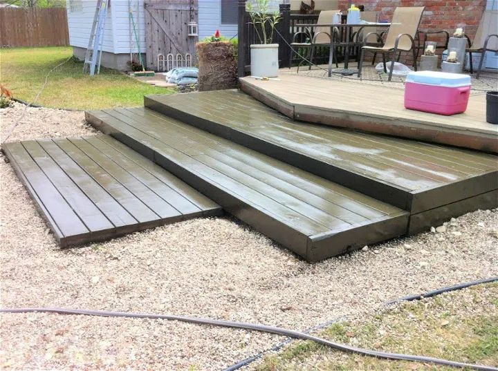 a wooden deck with steps leading up to the back door and patio furniture in the background