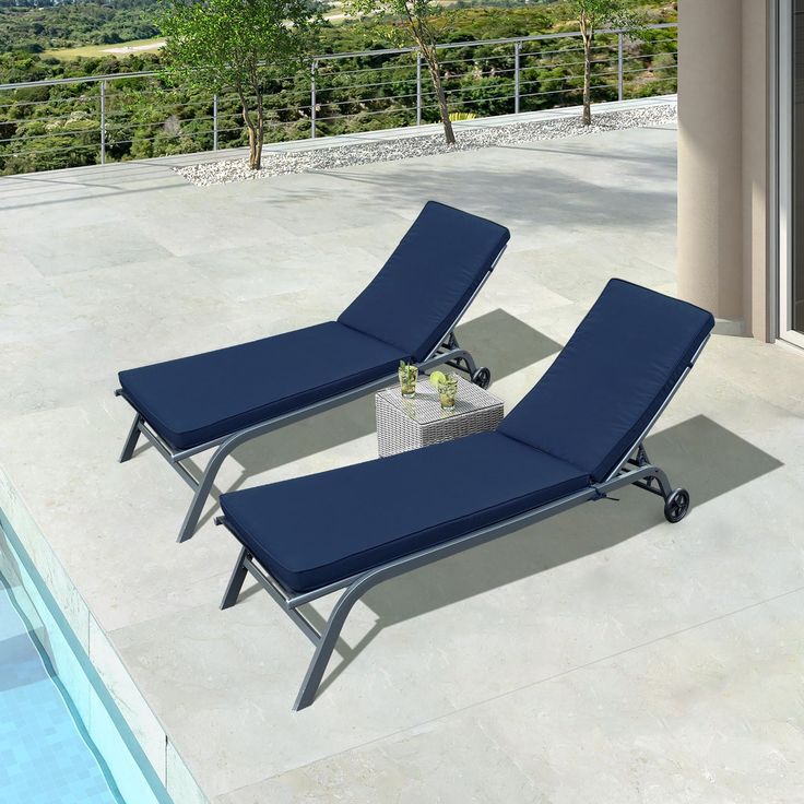 two chaise lounge chairs sitting next to a swimming pool