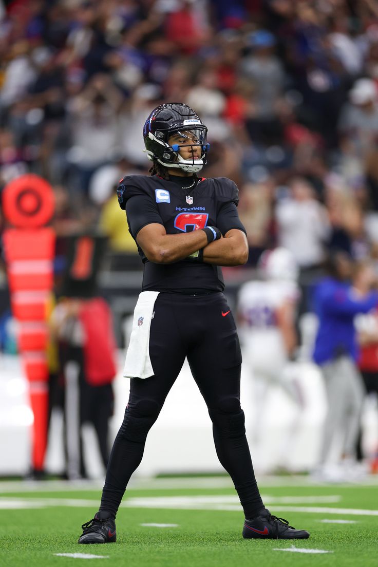 a football player standing on the field with his arms crossed