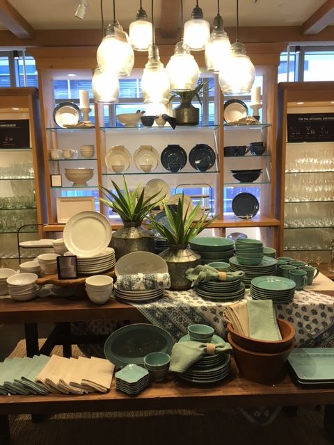 a table with plates and bowls on it in front of a display case filled with dishes