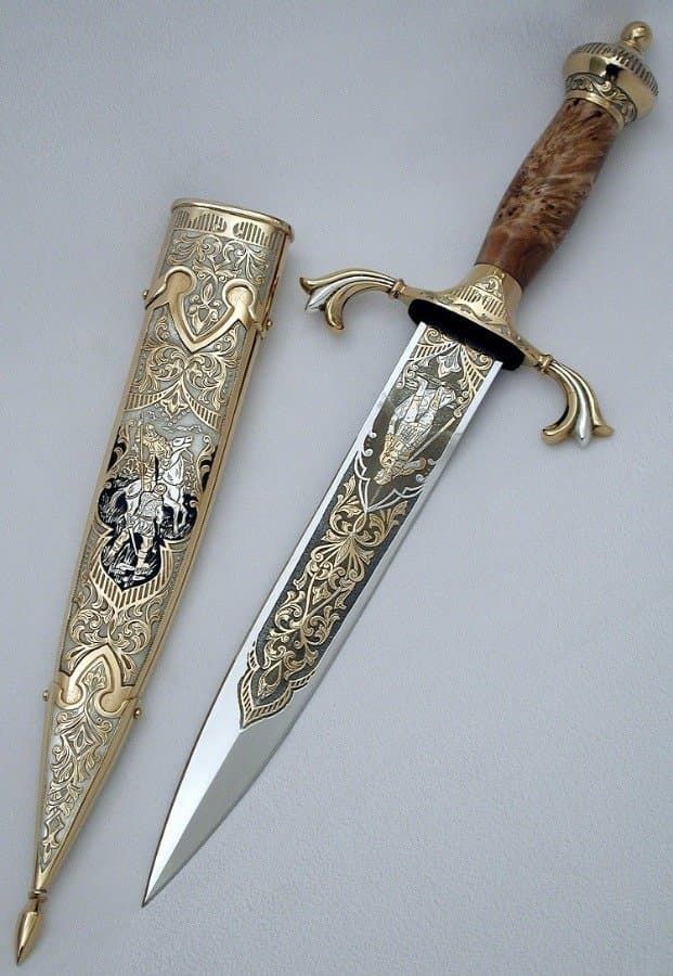 two different types of knifes on a white table with silver and gold trimming