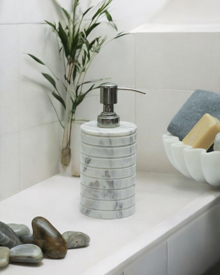 a soap dispenser sitting on top of a counter next to some rocks