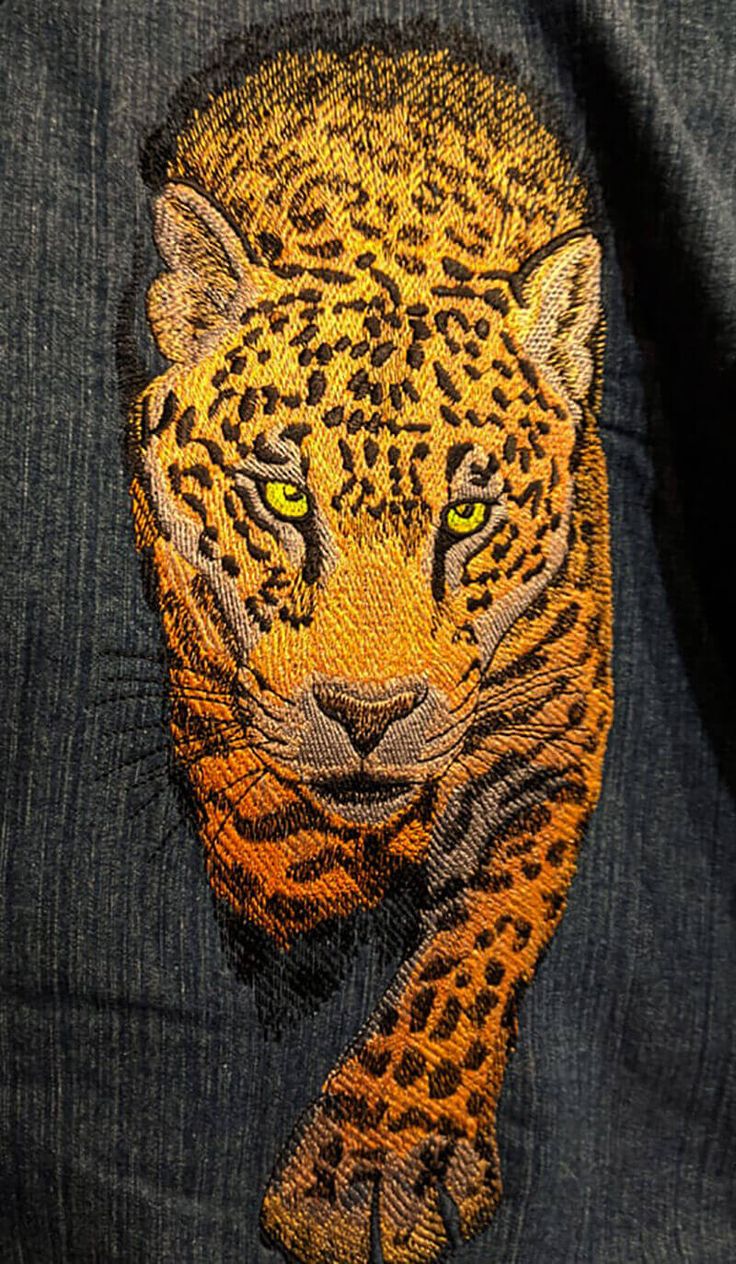 a close up of a person wearing a jean jacket with an image of a leopard on it