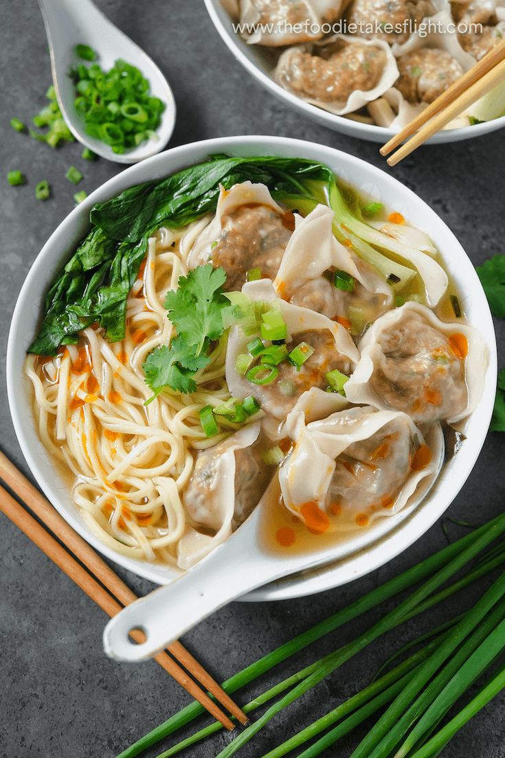 two bowls filled with meat and noodles next to chopsticks