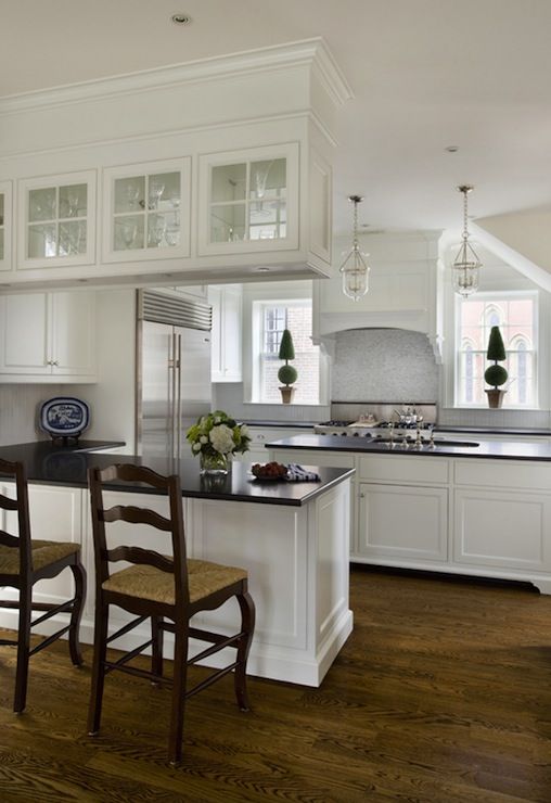 a large kitchen with white cabinets and wooden floors