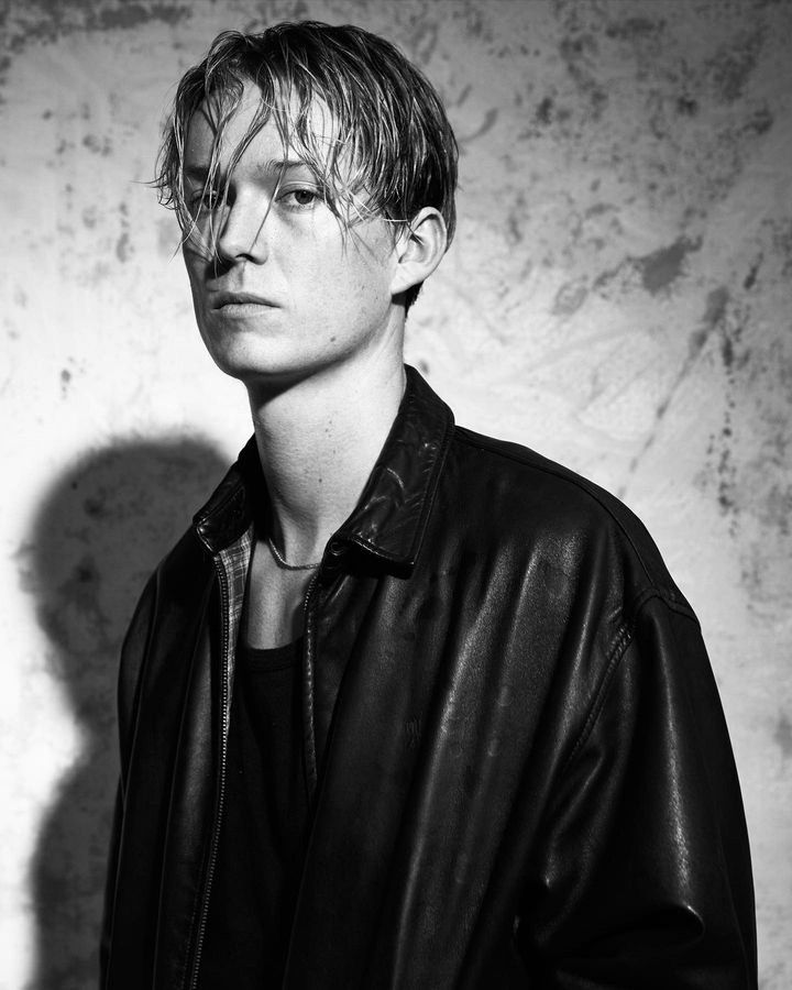 a young man in a leather jacket poses for a black and white photo