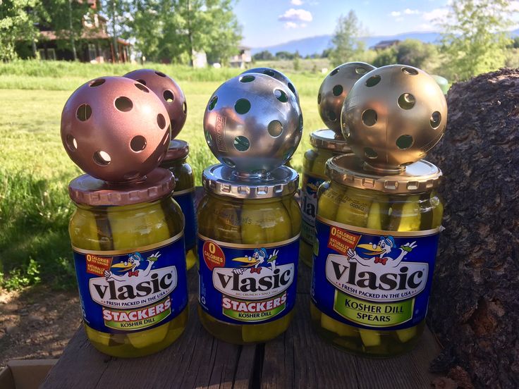 three jars of pickles sitting on top of a wooden table