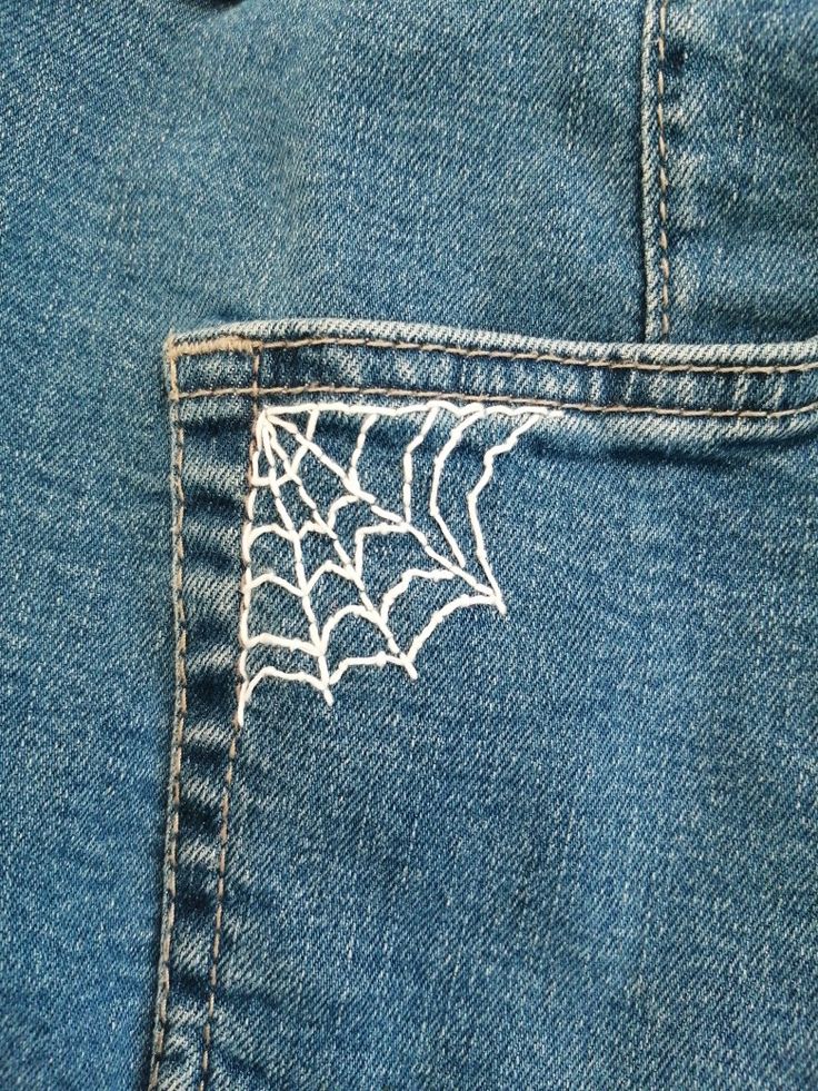 A white spider web embroidery on blue jeans pocket Embroidery On Jeans Tutorials, Fashion Design Embroidery, Cool Embroidery Designs On Jeans, Embroider Spider Web, Embroidery Patterns Pants, How To Embroider Spider Web, Jean Patches Ideas Embroidery, Embroidery Design On Jeans, Sewing Designs On Jeans