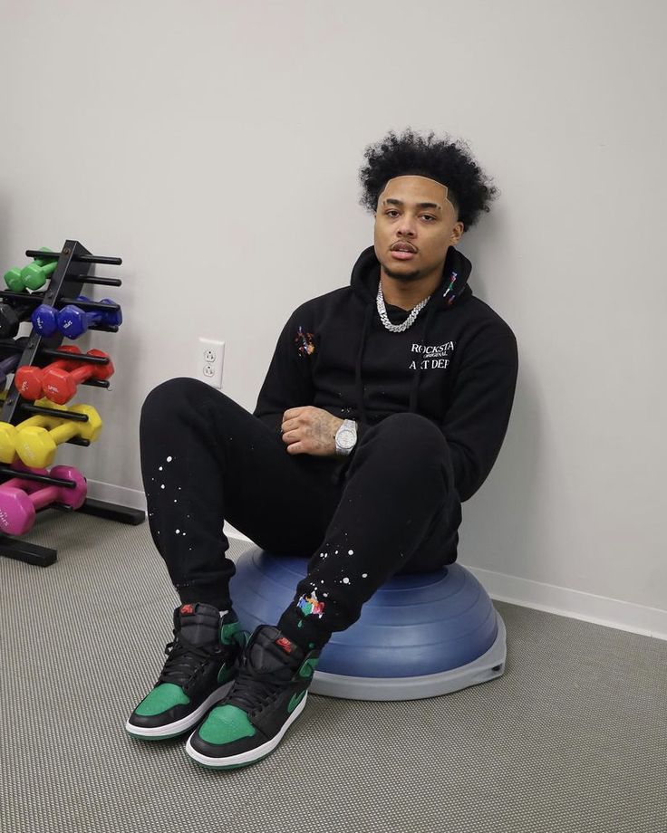 a man sitting on top of a blue ball in front of a rack of colorful shoes