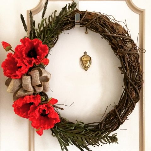 a wreath with red flowers is hanging on the front door