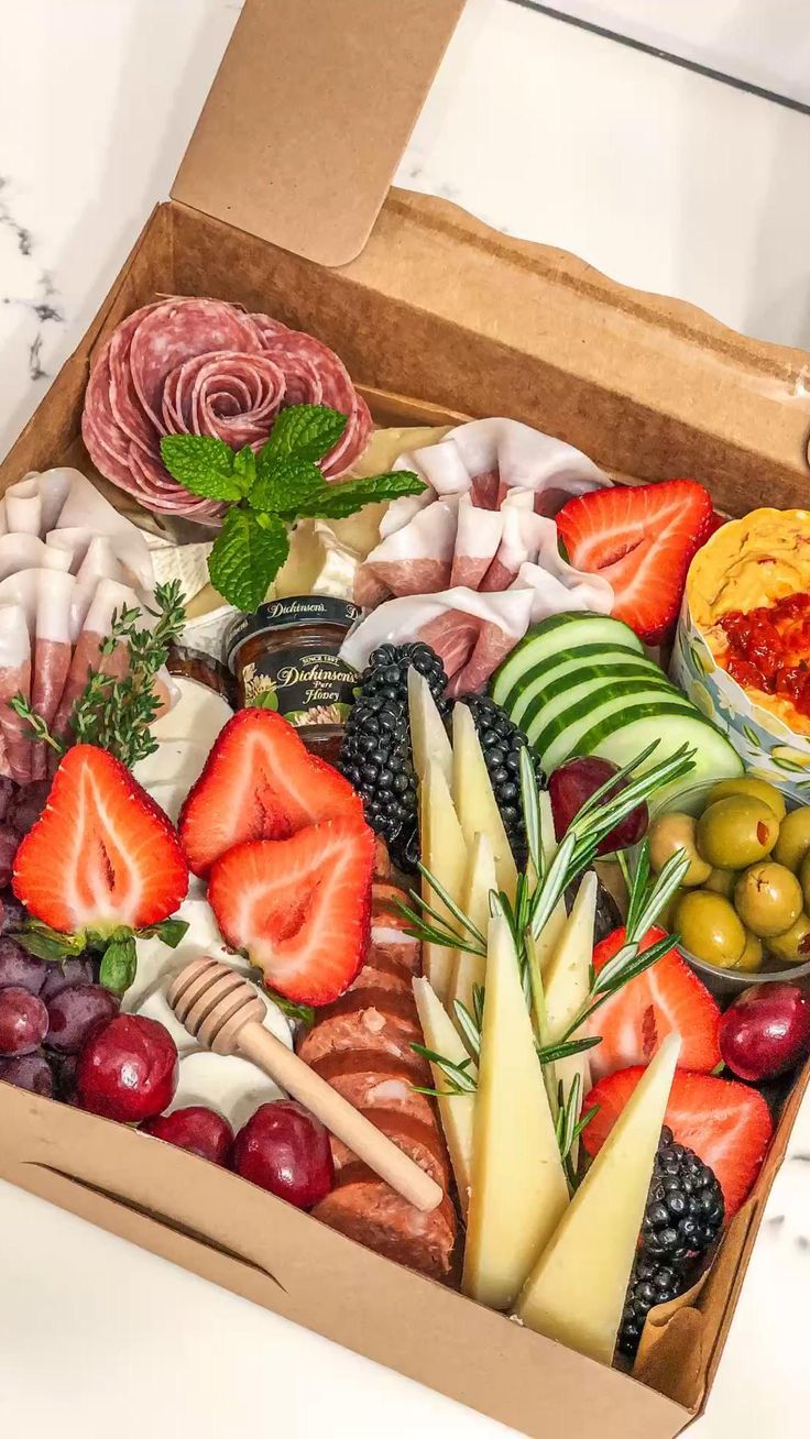 a box filled with assorted fruits and meats on top of a marble counter