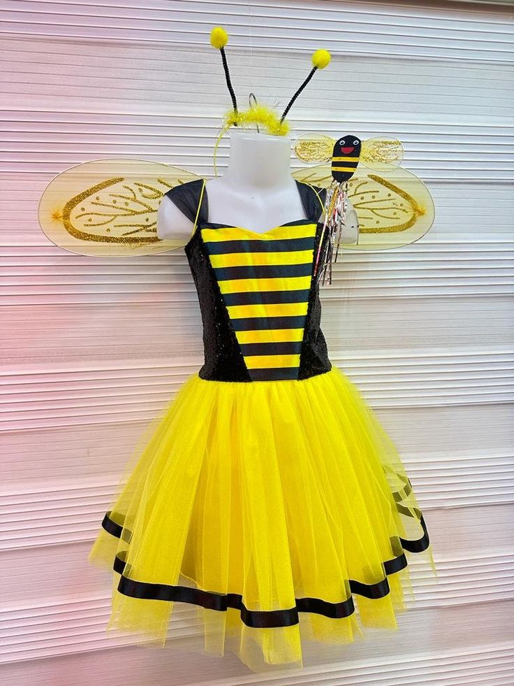 a dress made to look like a bee with yellow and black stripes is hanging on a wall