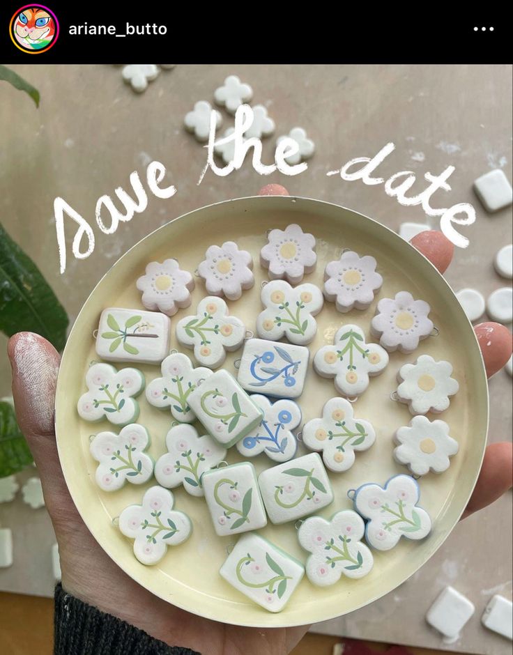 a person holding a plate with flowers on it and the words save the date spelled in small letters