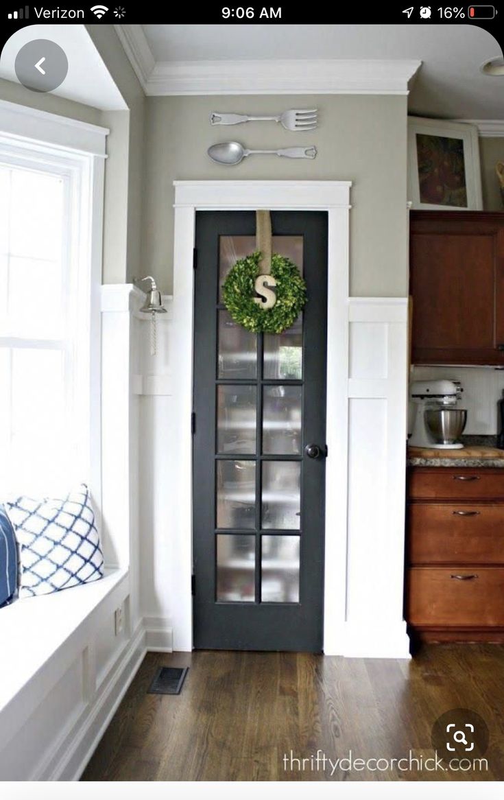 a kitchen with wood floors and white walls, has a glass door that leads to the breakfast nook