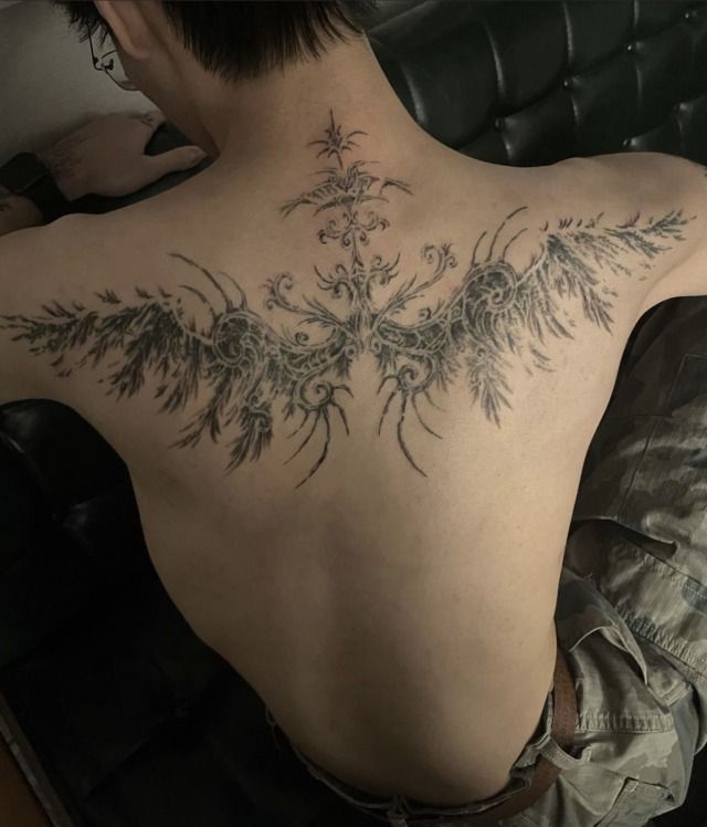 the back of a man's neck with an intricate tattoo design on his chest