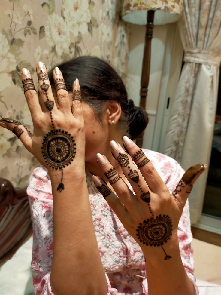 a woman is holding her hands up with henna tattoos on it's arms