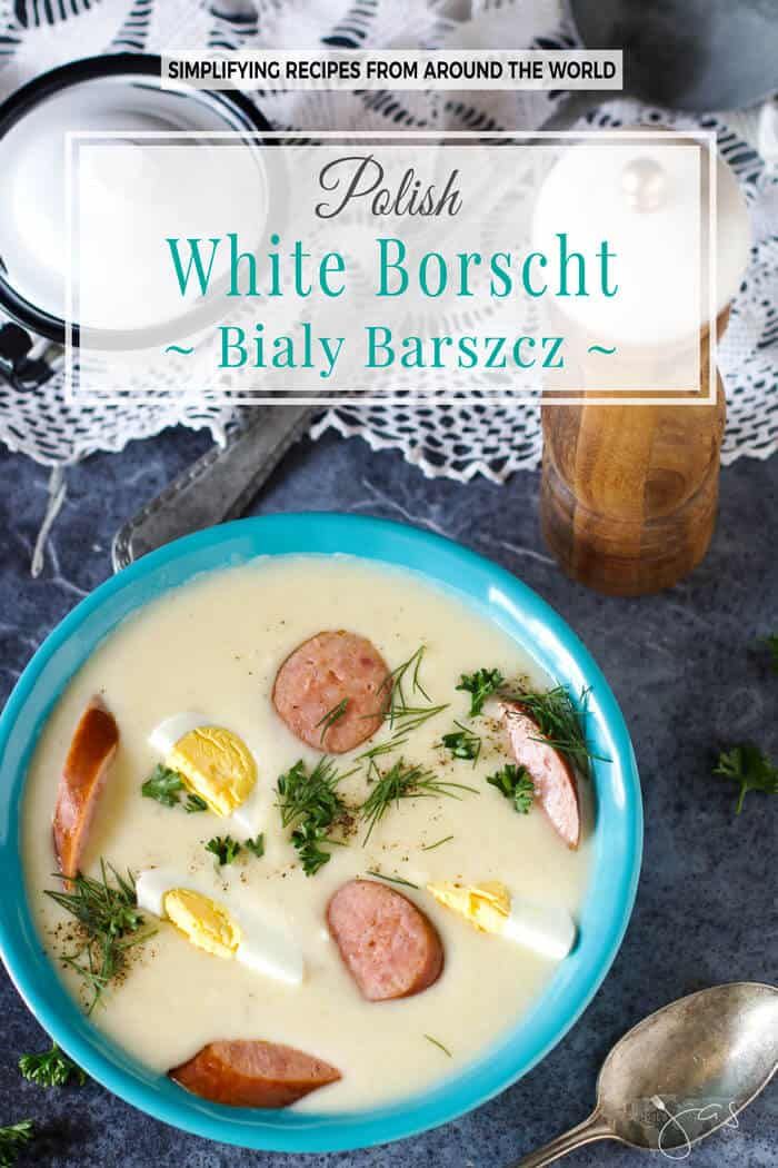 white borsch with sausage and eggs in a blue bowl next to a spoon