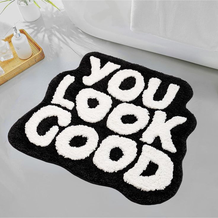 a black and white rug with the words you look good on it next to a bathtub