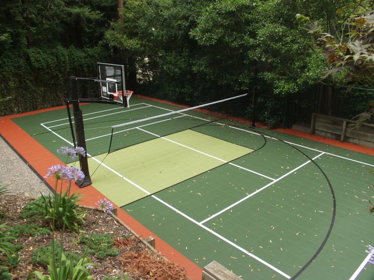 an outdoor basketball court surrounded by trees and flowers in the middle of a garden area