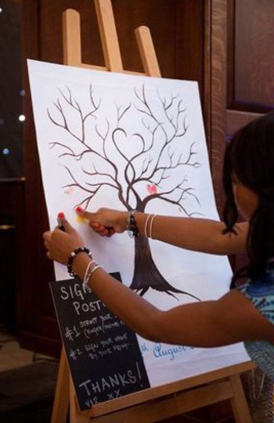 a woman is painting a tree on an easel with chalk and pencils in front of her