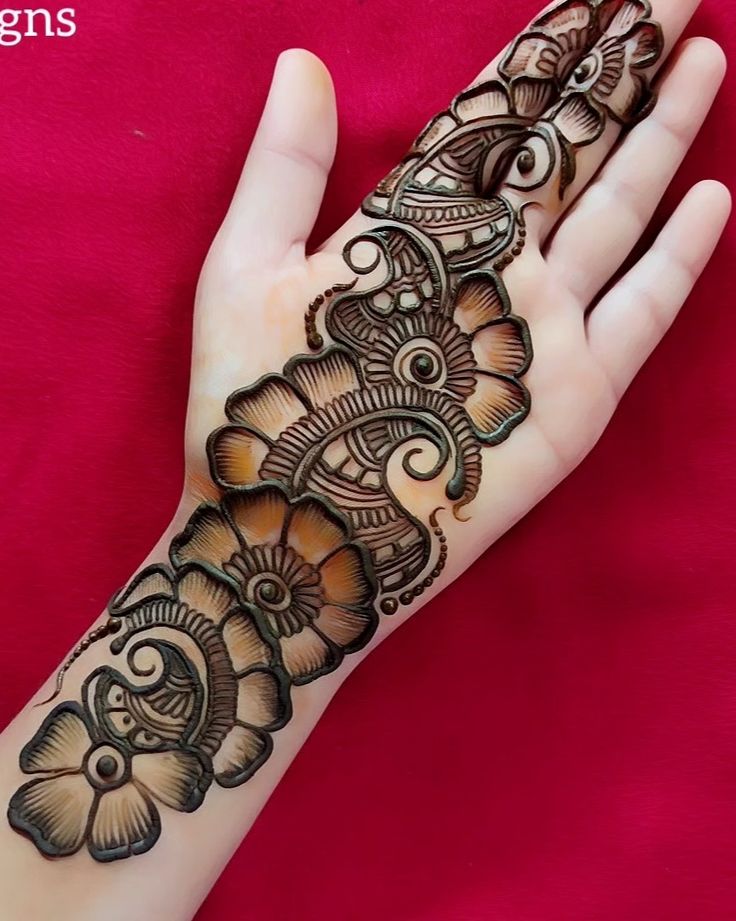 a woman's hand with henna tattoos on it and the design on her arm