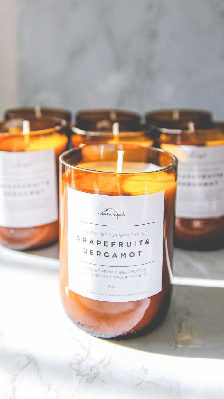 several candles are sitting on a table with labels in front of them that read grapefruit bergamot