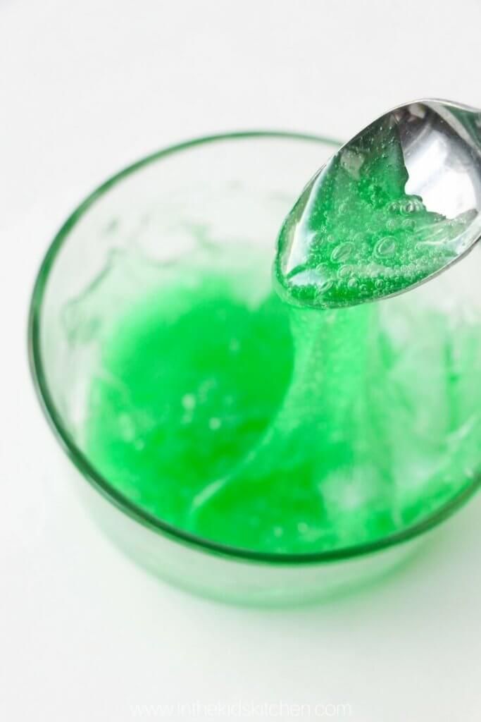 a green liquid in a glass with a spoon