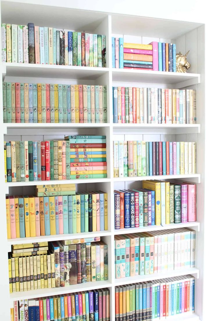 a bookshelf filled with lots of colorful books on top of white shelves in a room