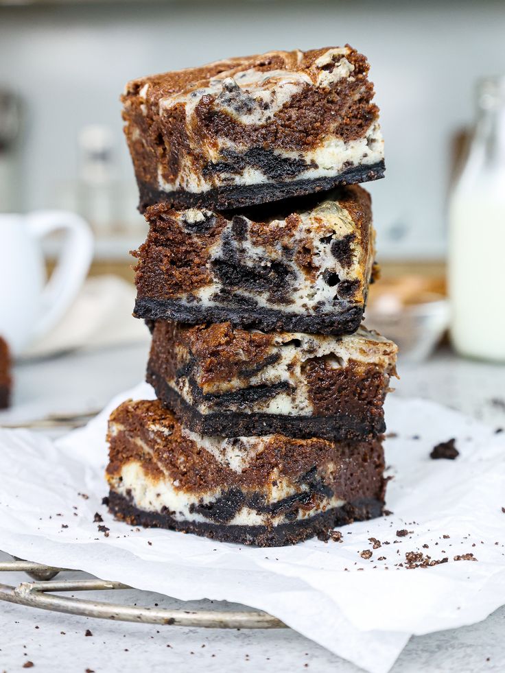 four brownies stacked on top of each other in front of a glass of milk