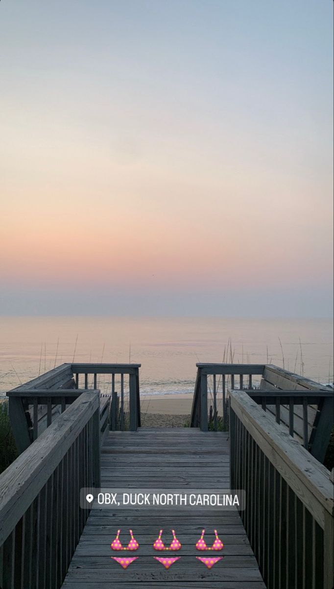 a wooden walkway leading to the beach at sunset